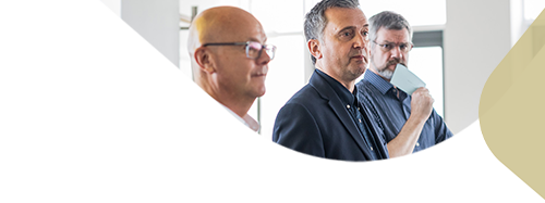 Three white men in business dress looking into a room