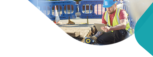 A site works engineer looking down a pavement that is dug up.