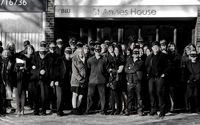 A black and white photo of team members in front of a building saying St Annes House