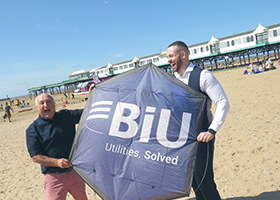 Two white men holding a kite with the BIU logo on